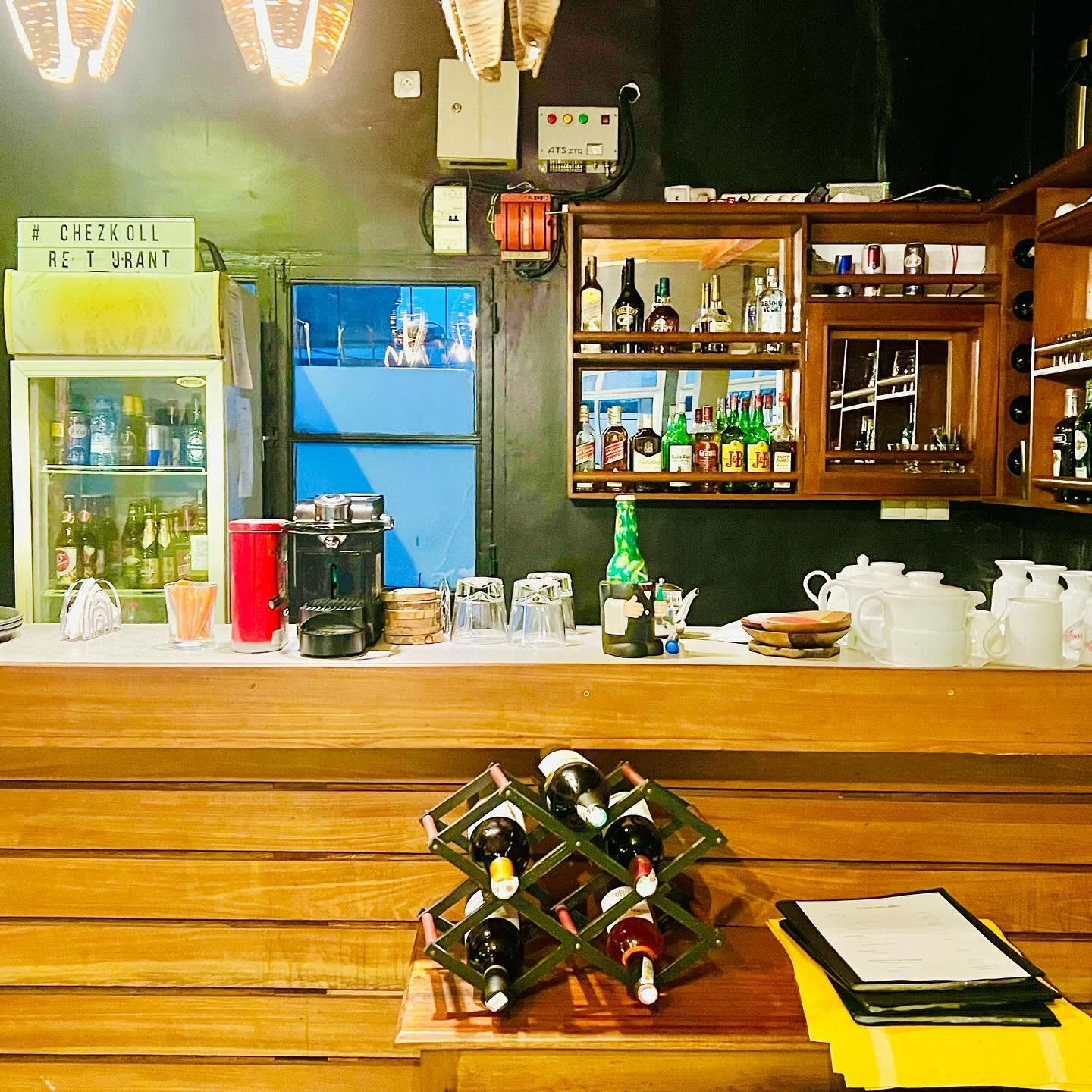 Le bar en bois de Chez Koll, ses bouteilles de vin et ses suspensions tressées