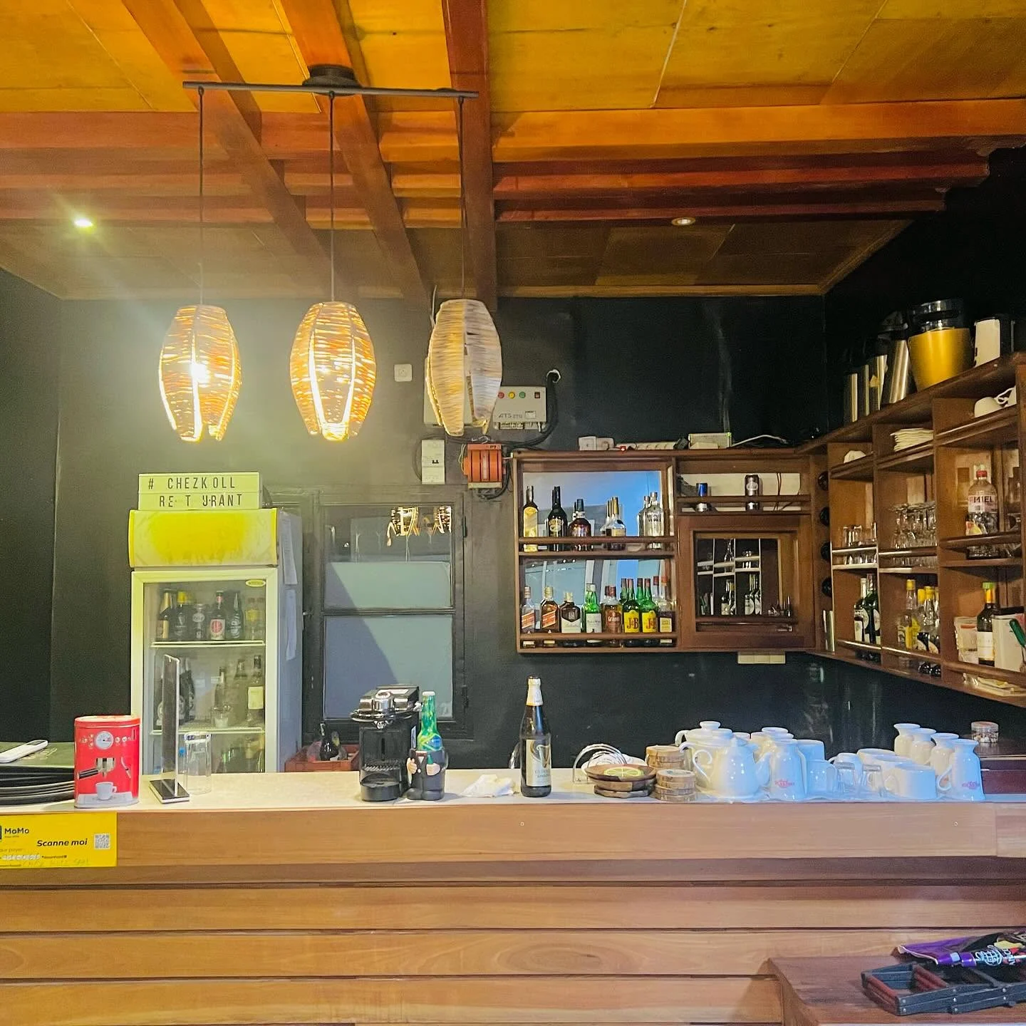 Des suspensions tressées éclairent chaleureusement le bar en bois de Chez Koll